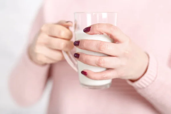 女性は牛乳のガラスのマグカップを保持しています。 — ストック写真