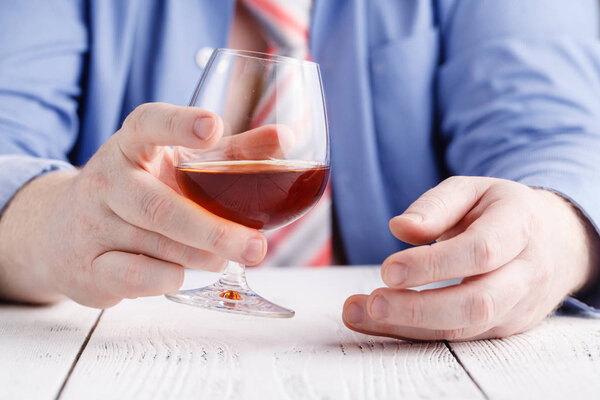 Мужчина держит в руке стекло о виски
