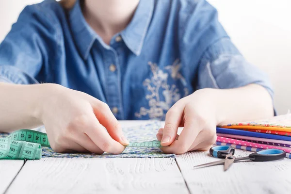 Image recadrée d'un beau jeune designer travaillant avec des croquis et du ruban à mesurer dans un salon de couture — Photo