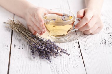 Kadın el ele tutuşarak cam Kupası'nda aromatik bitki çayı