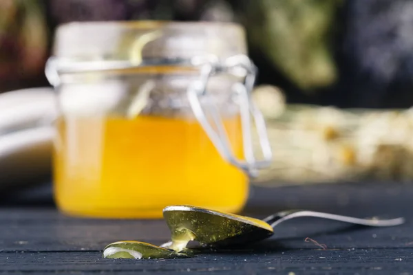 Gyllen honning i glasskrukke på rustikke bord – stockfoto