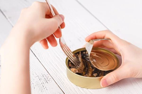 Pescado abierto puede con las manos y tenedor en la mesa — Foto de Stock