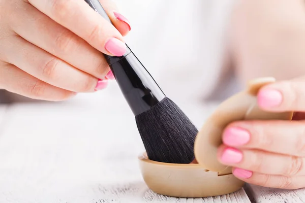 Primer plano del cepillo de maquillaje con frasco de polvo cosmético suelto en la mano — Foto de Stock