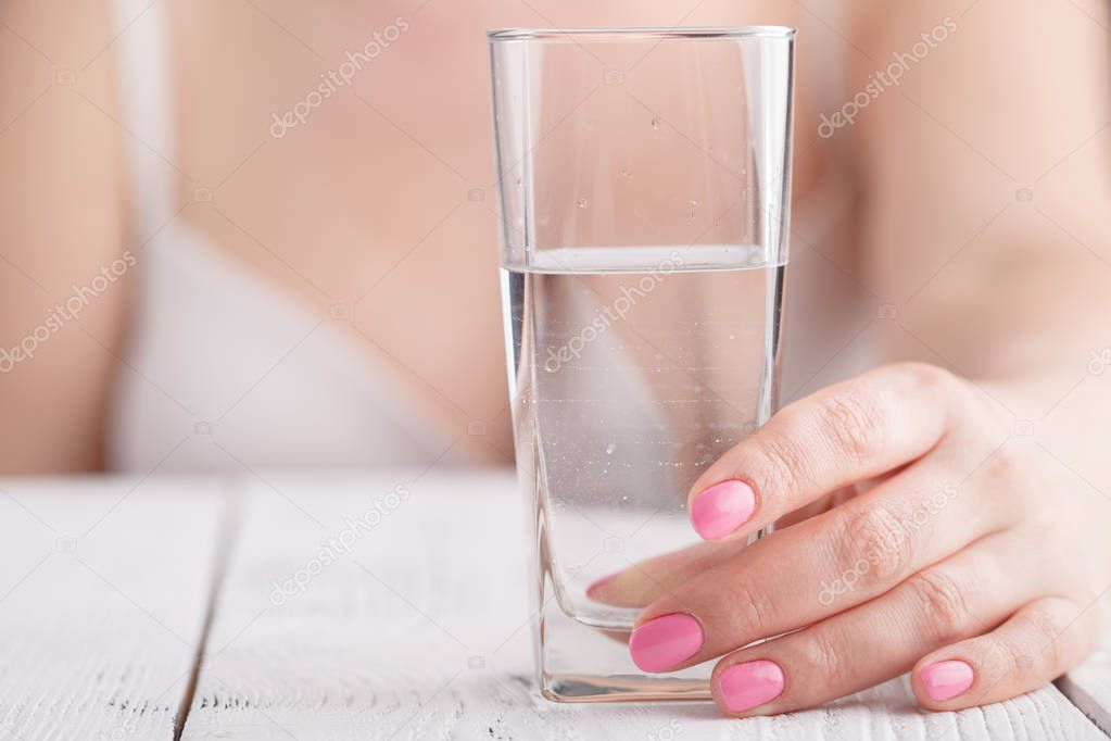 Splash of clear water in glass in female hands