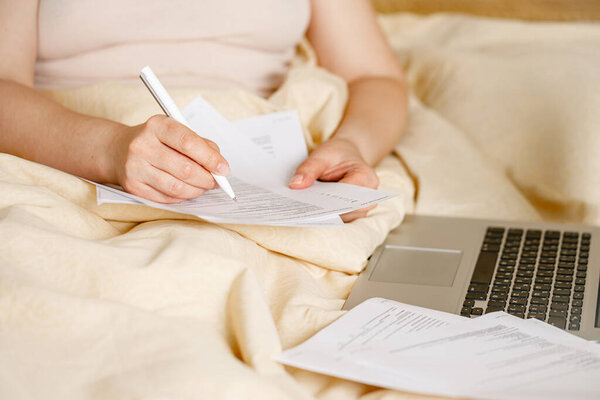 Woman employee in bed with laptop computer in self isolation working from home, coronavirus covid-19 quarantine. Remote working of business worker, online education. Prevention of virus spread