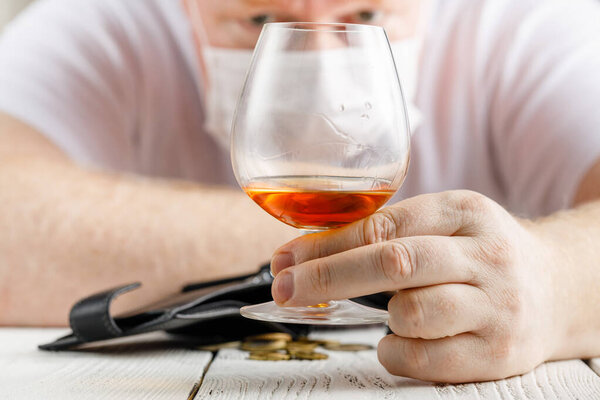 Взрослый мужчина пьет алкоголь домашнего карантина, вызванного коронавирусом
