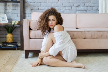 Rahat ve rahat bir kız zamanı. Koltukta oturan tatlı bayan. Gülümseyen, evde rahat bir atmosferde oturan, bitkilerle ve güzel tasarımla