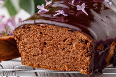 Brownie, ahşap arka planda çikolatayla sulandırılmış, bir buket leylakla.