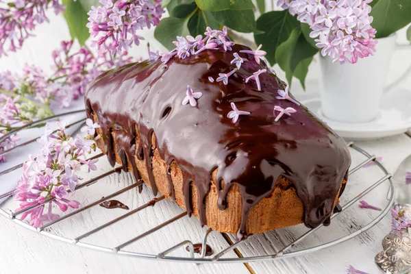 Brownie, ahşap arka planda çikolatayla sulandırılmış, bir buket leylakla.