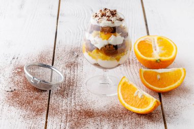 Güzel bardaklarda kremalı ıvır zıvır ve beyaz ahşap arka planda taze meyve kesme - sağlıklı yeme kavramı