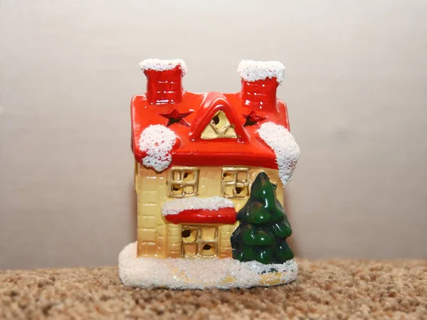 Een klein speelgoedhuisje in een sneeuwoutfit en een rood dak. — Stockfoto