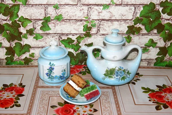 On the table is an old porcelain teapot and a saucer with dessert. — Stock Photo, Image