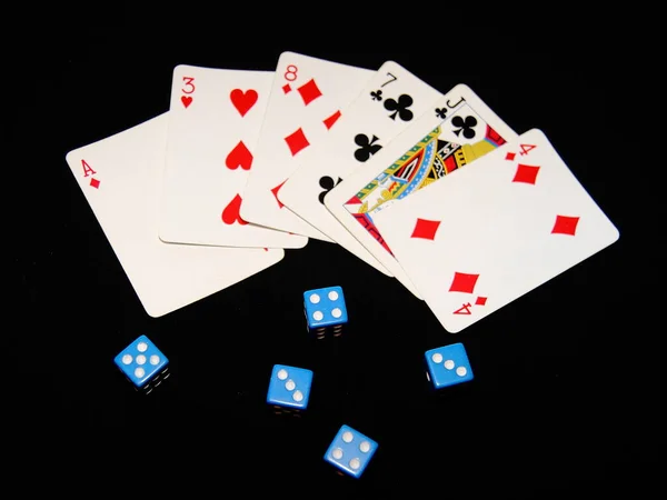 Playing cards and dice are scattered on a black background.