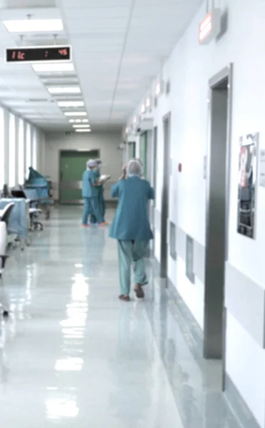 Doctors and nurses walking in hospital hallway, blurred motion.