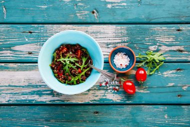 Vegan salata quinoa, domates ve roka turkuaz vintage tablo üzerinde mavi seramik kase. Görünümü en çok, uzay kopyalayın. Enerji artırma gıda kavramı. Düz yatıyordu