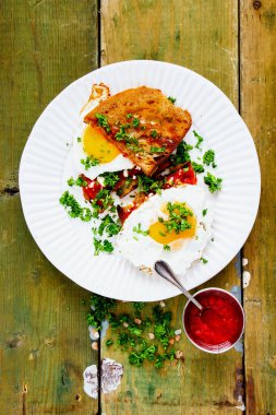 Eski ahşap masanın üzerinde ızgara ekmeğin üzerinde taze bitkilerle sade yumurta.