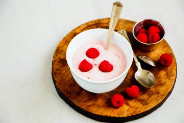 Ahşap kesim tahtasında taze böğürtlenli ahududu yoğurdu.