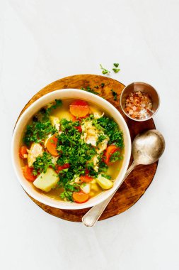 Tahta kesme tahtasının üzerinde somon dolu kırmızı balık çorbası. 