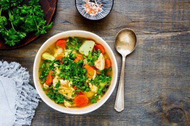 Kasede balık çorbası, somon ve ahşap masada taze otlar.