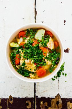 Somon balıklı balık çorbası ve yakın plan taze otlar.