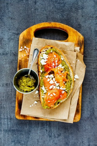 Smoked salmon toast with pesto and feta on vintage table flat lay