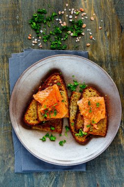 Tütsülenmiş somon ve ızgara ekmeğin üzerine taze otlar.