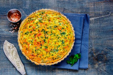 Klasik peynirli kiş, ahşap arka planda taze bitkiler.