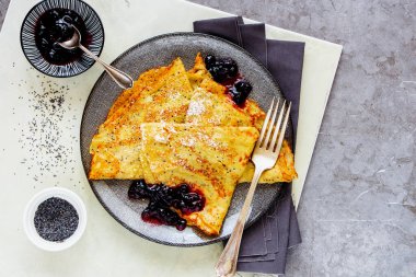 Hafif arka planda yabanmersini reçeli ev yapımı haşhaşlı krep.