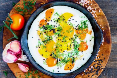 Sıcak, siyah bir tavada taze dereotlu yumurta ve domates.