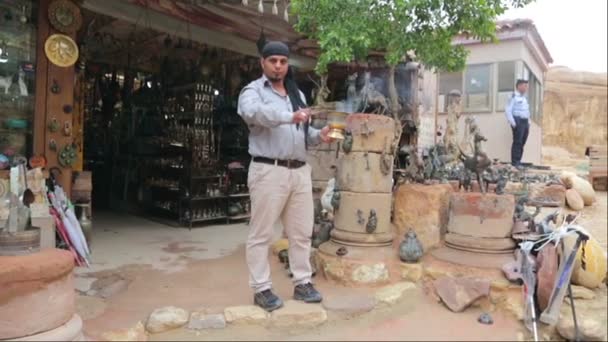 Bedouin kindles coals for hookah outside a souvenir shop — ストック動画
