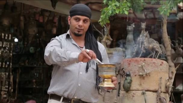 Bedouin kindles coals for hookah outside a souvenir shop — Stock Video