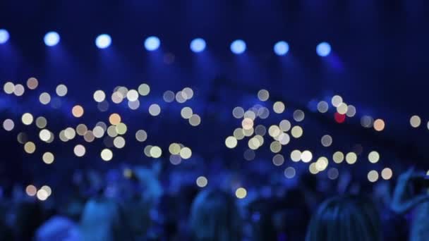 O público está brilhando com lanternas de telefones . — Vídeo de Stock
