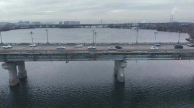 Kışın geniş bir nehrin üzerindeki köprüde trafik vardı..