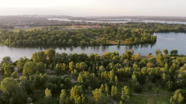 Заміські будинки біля великої річки на заході сонця, повітряні — стокове відео