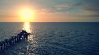 Silhouette of a pier over the water at sunset.