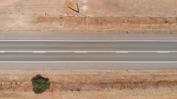 Top down view flying over desert road with trucks — ストック動画