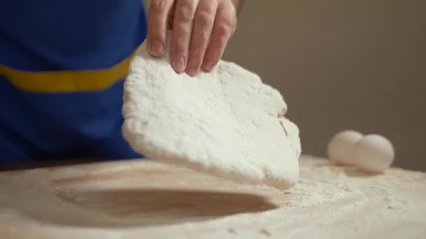 L'uomo stende l'impasto sul tavolo della cucina . — Video Stock