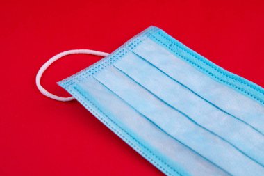 Tıbbi maske. Kırmızı arka planda tıbbi koruyucu maskeler. Tek kullanımlık yüz maskesi ağız ve burnu kapatır. Sağlık ve tıbbi konsept. Mavi tıbbi tek kullanımlık yüz maskesi, kırmızıya yakın..