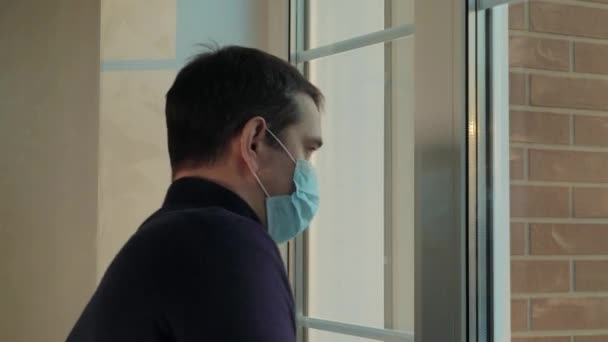 De man komt het huis binnen met een medisch masker. Pandemie. — Stockvideo