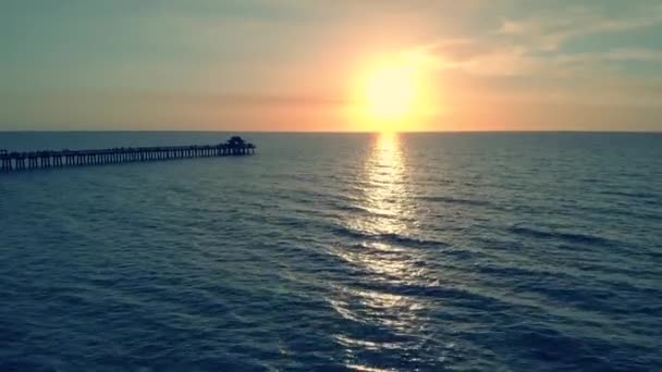 Silhueta escura de um cais sobre a água ao pôr-do-sol — Vídeo de Stock