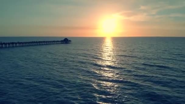 Silhouette sombre d'une jetée au-dessus de l'eau au coucher du soleil