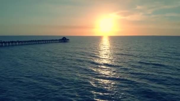 Silhouette sombre d'une jetée au-dessus de l'eau au coucher du soleil — Video