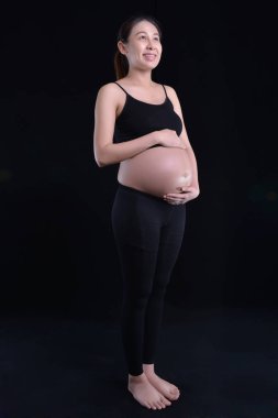 Siyah arka planda hamile bir kadın.