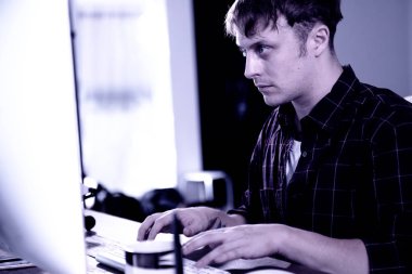 Bir bilgisayara evlerinde çalışan genç bir adam.