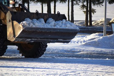Traktör parktaki karı kaldırır