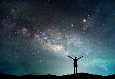 Samanyolu Gökadası ile manzara. Gece gökyüzünde yıldızlar ve siluet mutlu adam dağ.