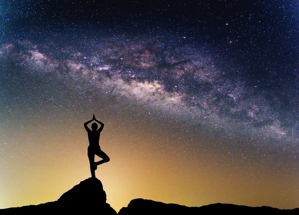 Landschaft mit Milchstraßengalaxie. Nachthimmel mit Sternen und Silhouette Frau praktiziert Yoga auf dem Berg. — Stockfoto