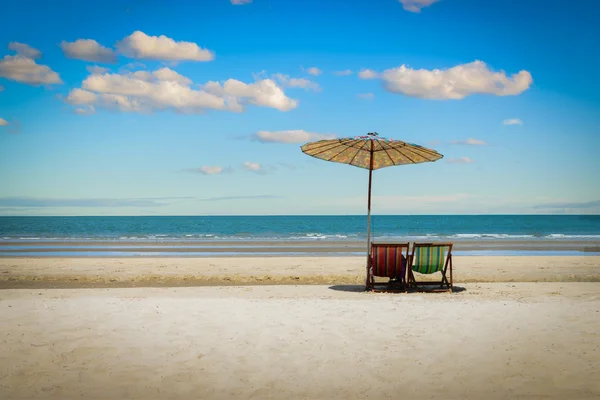 Cadeiras de praia na praia de areia com fundo céu azul nublado . — Fotografia de Stock