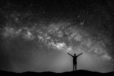 Manzara siyah beyaz görüntü ile Samanyolu. Gece gökyüzünde yıldızlar ve siluet mutlu adam dağ.