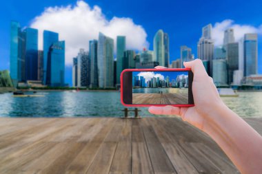 Bir cep telefonu, Singapur şehir manzarası downtown içinde gündüz ticaret bölgesinin resimleri alarak kız.